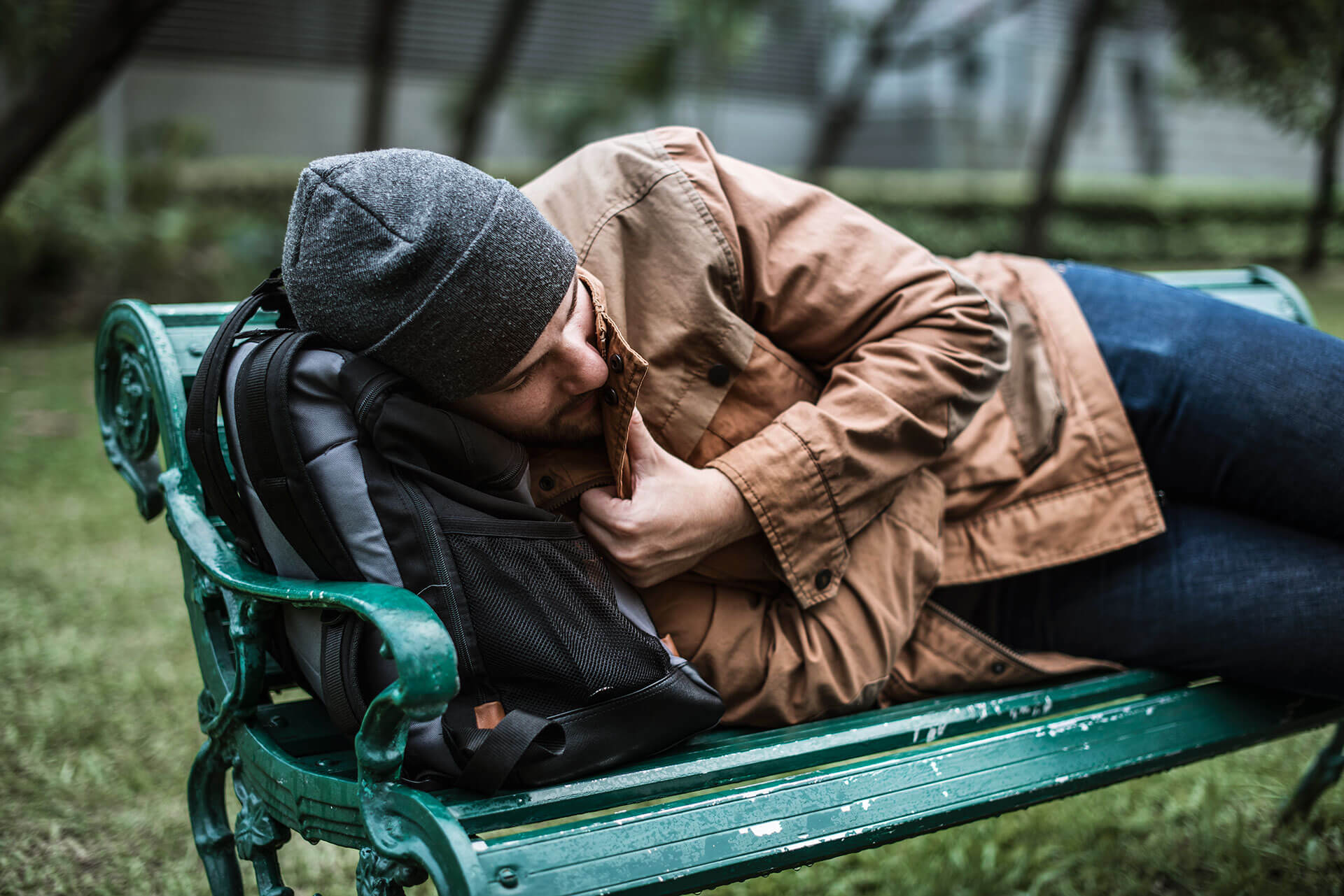 homeless adult man sleeping on bench in the park