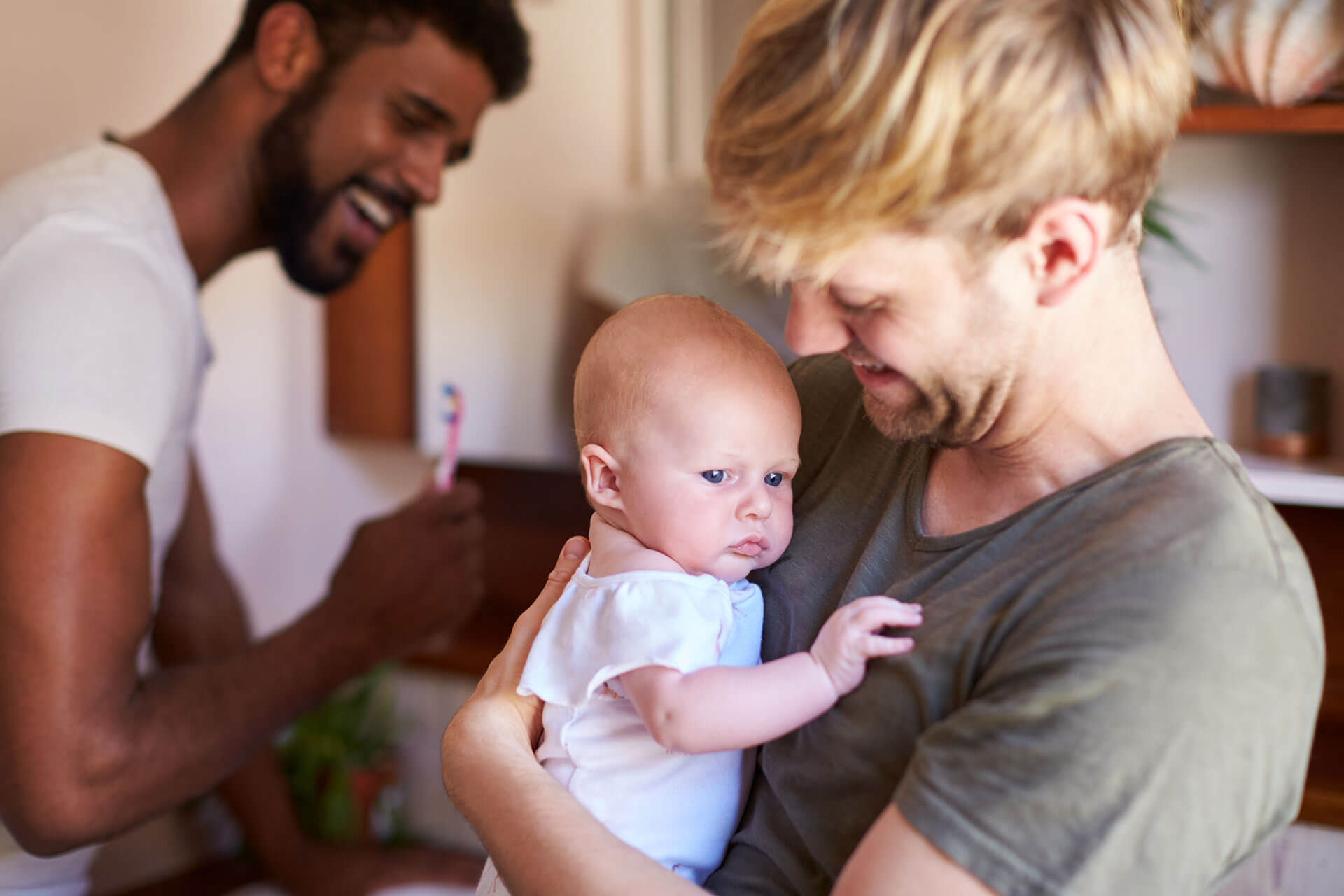 loving male same sex couple cuddling baby daughter loving male same sex couple cuddling baby daughter