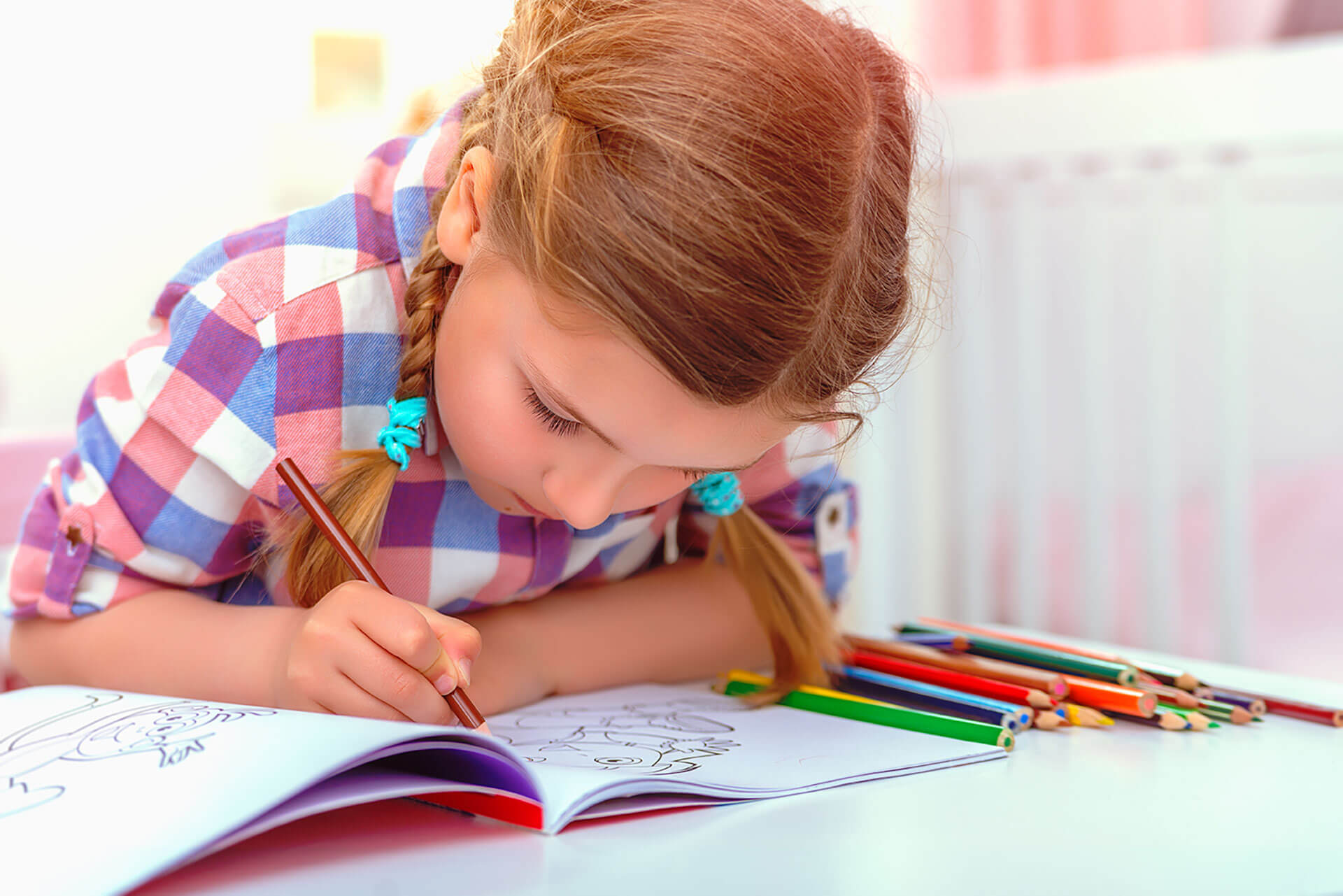 a young girl is colouring in with pencils in a colouring book