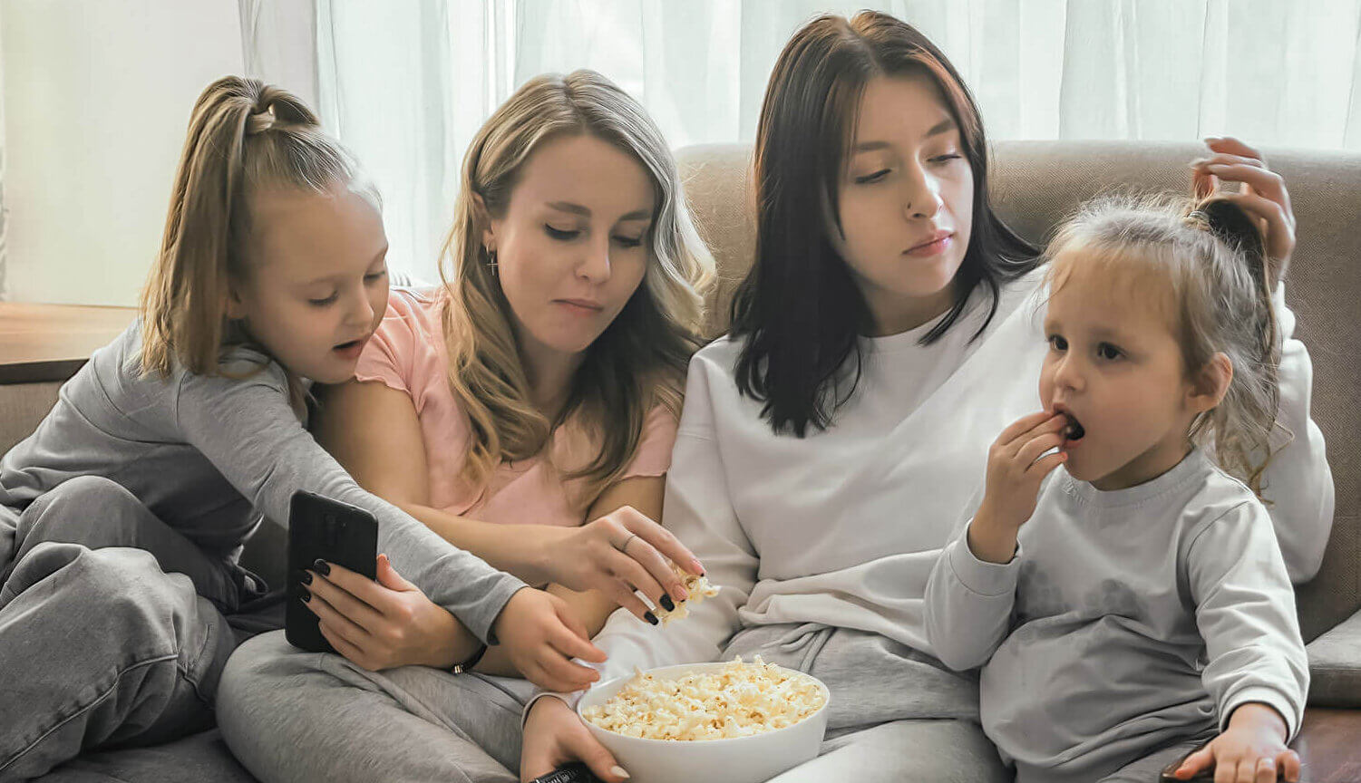 A family sit around on a sofa eating popcorn A family sit around on a sofa eating popcorn